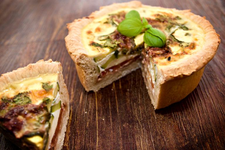 Un delicioso quiche mediterr&aacute;neo de capas profundas con guarnici&oacute;n de albahaca.