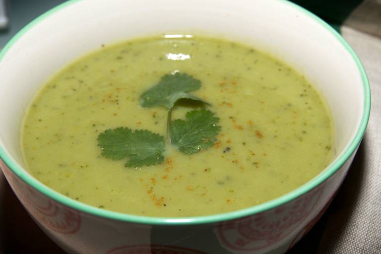 Sopa de berros con una ramita de cilantro como guarnici&oacute;n en un taz&oacute;n blanco con borde verde.